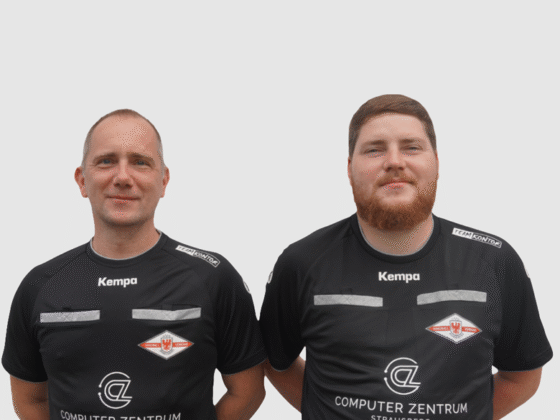 Zwei Männer in schwarzen Sporttrikots mit den Logos von Kempa und Computer Zentrum stehen nebeneinander vor einem schlichten weißen Hintergrund und blicken als Schiedsrichter Handball in die Kamera.