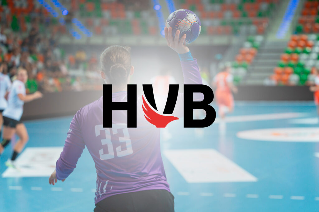 Ein Handballspieler im lila Trikot mit der Nummer 33 bereitet sich während eines Handballspiels in Brandenburg in einer Halle auf den Wurf vor. Im Hintergrund sind Zuschauer und Spieler zu sehen. Der Schriftzug HVB mit einem roten Flügellogo ist über das Bild gelegt.