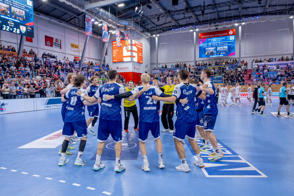 Die Handballspieler in blau-weißen Trikots stehen während des HVB-Pokal-Final-Four-Turniers 2026/27 auf dem Spielfeld im Kreis und haben die Arme umeinander gelegt.