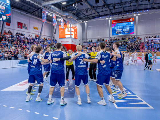 Die Handballspieler in blau-weißen Trikots stehen während des HVB-Pokal-Final-Four-Turniers 2026/27 auf dem Spielfeld im Kreis und haben die Arme umeinander gelegt.